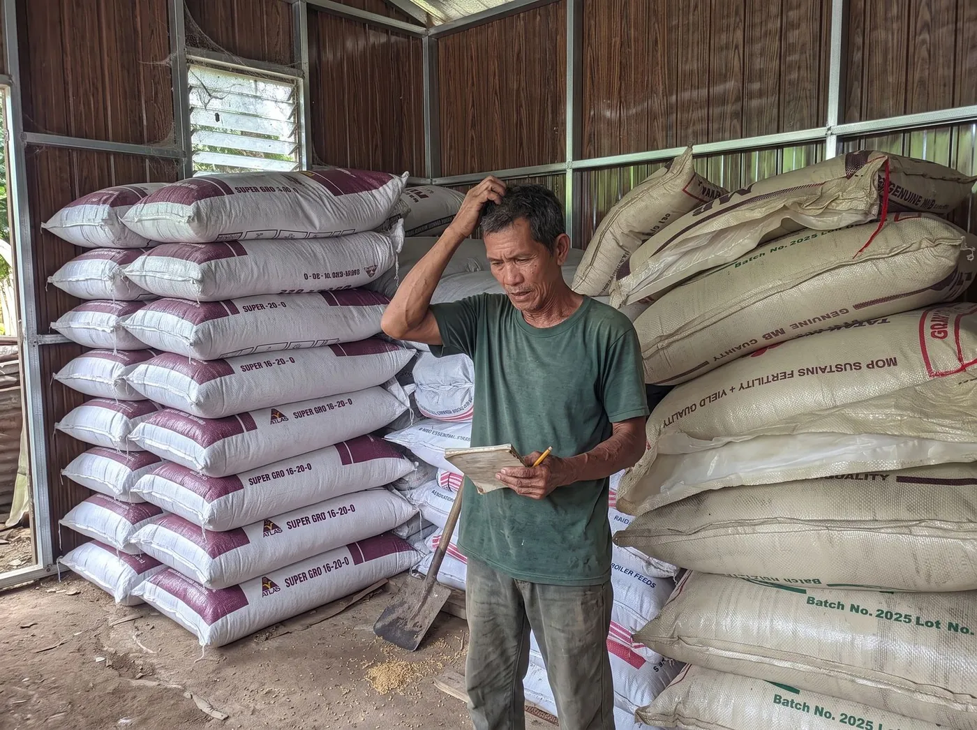 A farmer among the fertilizer sacks in his shed, working out his notebook